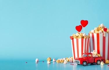 Wall Mural - Create a memorable cinematic Valentine's with food delivery. Side view table accents include tiny car model, striped popcorn boxes, heart decor, sprinkles. Light blue wall backdrop sets perfect scene