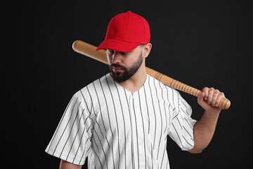 Wall Mural - Man in stylish red baseball cap holding bat on black background
