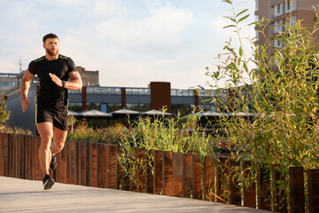 Canvas Print - Young man running outdoors on sunny day. Space for text