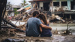 © Artyom - Couple sitting on debris, embracing, looking at a flooded, destroyed home