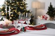 © New Africa - Christmas table setting with burning candles, gift box and dishware indoors