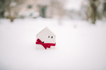 Wall Mural - Merry Christmas and 2024 happy new year banner with small toy model house on a white snow background. Miniature white toy house model