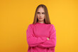 Resentful woman with crossed arms on orange background