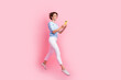 © deagreez - Full size profile photo of excited nice girl jump use smart phone empty space ad isolated on pink color background