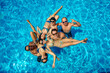 Group of happy young friends are having fun and posing for photo in swimming pool together