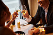 © LIGHTFIELD STUDIOS - joyful gentleman in elegant attire holding hand of girlfriend and clinking glasses during date