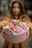 Fototapeta  - Gift box with roses and macaroons in the hands of a pretty woman