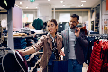 Wall Mural - Young woman and her boyfriend shopping at clothing store.