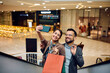 Happy couple taking selfie while shopping at mall.