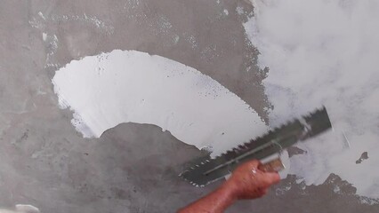 Wall Mural - Worker puts finishing layer of stucco on the wall using a plastering trowel