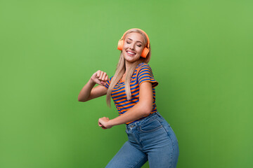 Wall Mural - Photo of funky lady wearing striped t shirt dancing pop music in orange headphones vibes nostalgia isolated on green color background