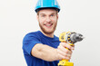 © Sanne Berg/peopleimages.com - Construction man, portrait and power drill in hand, studio and maintenance by white background. Person, employee or small business owner with tools, helmet or happy for job at repair services company