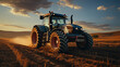 A Tractor Pulling A Grey Planter On A Empty Field on Blurry Background