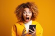 An astonished young woman in a yellow jacket reacts vividly to content on her phone, her wide-eyed expression and open mouth conveying surprise and excitement