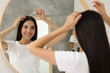 © New Africa - Beautiful woman applying hair serum in bathroom. Cosmetic product