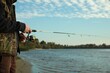 © New Africa - Fisherman with rod fishing at riverside, closeup