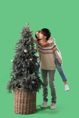 Wall Mural - Cute girl and her brother decoration Christmas tree on green background