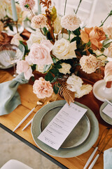 Wall Mural - Bouquet of flowers stands on the festive table next to a plate with a menu