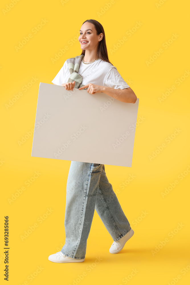 Young woman with credit card on yellow background