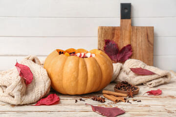 Wall Mural - Tasty mulled wine in pumpkin and ingredients on white wooden background