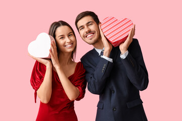 Canvas Print - Beautiful young couple with gift boxes on pink background. Valentine's day celebration