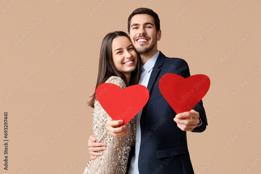 Beautiful young couple with red paper hearts on brown background. Valentine's day celebration