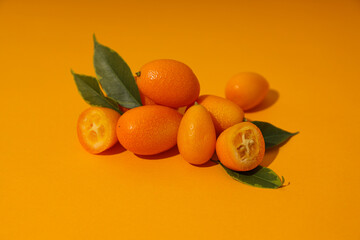 Sticker - Kumquat and leaves on orange background, close up