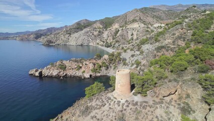 Wall Mural - Medieval watchtower next to cliffs on the Mediterranean coast. Orbital aerial view of medieval ruins next to the stunning blue sea and cliffs. Andalusia. Spain.