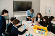 © Drobot Dean - Kids and teacher using constructor blocks and tablet while studying robotics in stem education class