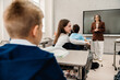 © Drobot Dean - Portrait of school girl turning back and talking to classmate while sitting in classroom