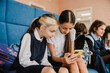 © Drobot Dean - Primary school girls using smartphone while sitting in school lobby