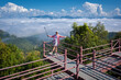 Asian traveler woman happy with the beautiful sea mist in the morning of mountain peaks the Thai language sign means Baan Huay Kong Mool Viewpoint of Sop Moei District Mae Hong Son, Thailand.