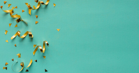 Wall Mural - close up on group of gold color of rolling ribbon and confetti on teal background with copy space fo