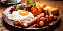 A Full Breakfast With Fried Eggs, Bacon, Sausages, Baked Potatoes And Fresh Fruit
