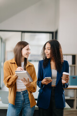 Happy two young business woman holding coffee cup in co-working office