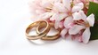 a pair of gold rings next to a bouquet of flowers
