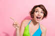 Photo of impressed cheerful lady wear green blue tank top showing finger looking empty space isolated pink color background
