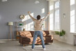 © Studio Romantic - Finally alone at home. Man happy to have some free time for himself. Tired family man enjoys freedom while wife and children are away. View from behind funny man standing in living room with hands up