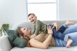 © Louis-Paul Photo - Mature mother with small son on sofa indoors, resting.