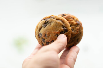 Two chocolate chip cookies in hand