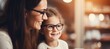 Girl trying glasses with ophthalmologist, blurred mother in background, copy space available