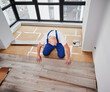 © anatoliy_gleb - Man laying laminate wood plank on floor underlayment in new flat. Top view of male construction worker installing laminate wooden flooring in living room. Home renovation concept.