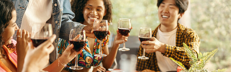 Group of happy young friends is drinking wine while having holiday dinner home party together