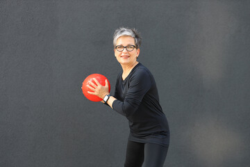 Poster - An athletic and fit mature woman enjoying outdoor exercise with a ball, embodying a healthy lifestyle.