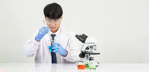 Wall Mural - Portrait Asian man student scientist Wearing a doctor gown in the lab looking hand at chemist. caused by mixing reagents in scientific research laboratories with test tubes and microscope on the table