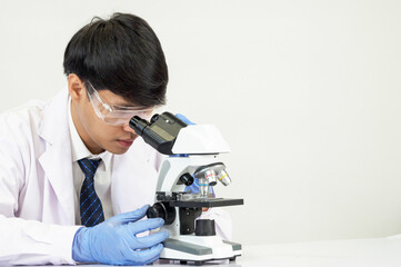 Wall Mural - Portrait Asian man student scientist Wearing a doctor gown in the lab looking hand at chemist. caused by mixing reagents in scientific research laboratories with test tubes and microscope on the table