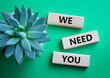 We need You symbol. Wooden blocks with words We need you. Beautiful green background with succulent plant. Business and We need You concept. Copy space