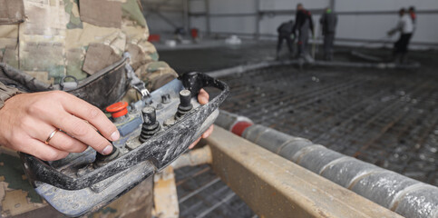 Poster - Worker holds control panel for concrete pump. Team of builders construction site is pouring cement