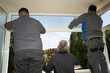 Obreros instalando un cerramiento de alumunio en la terraza de una casa.	