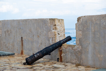 Wall Mural - Antique cannon put on opening of Firkas Fortress worn wall at Old Town of Chania Crete, Greece.